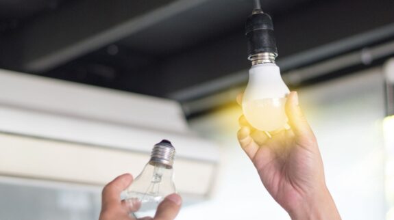 Ahorro de luz en el sector HORECA (1) Persona cambiando el foco de luz para ahorrar energía en la oficina de Apolo Energies